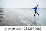 Caucasian woman in a blue sweater is skating on a frozen lake. The figure skater performs the program.