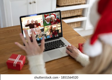 Caucasian woman at christmas, having video chat with friends and family using laptop, sitting at home in kitchen wearing santa hat and waving. social distancing during covid 19 pandemic at christmas - Powered by Shutterstock