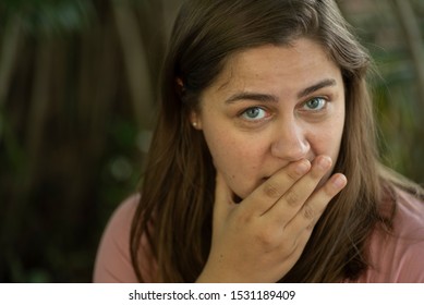 A caucasian woman covers her mouth with her hand with eyes wide open with an oops expression - Shutterstock ID 1531189409