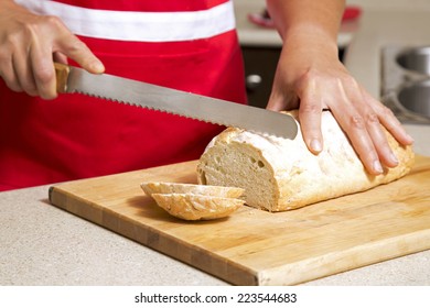 Caucasian Woman Cutting A Bread With Knife In Kitchen