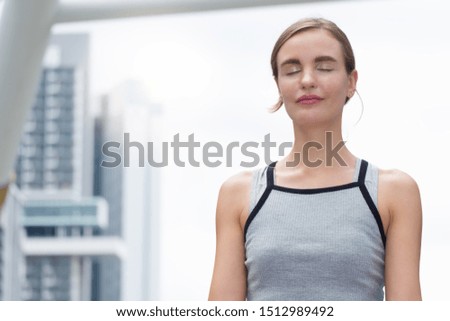 Young, tall woman sits in a summer dress on the beach of the Baltic Sea and smiles