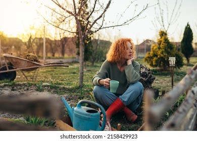 Caucasian Woman Drinking Coffee While Plants Flowers In Her Backyard Garden