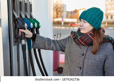 Caucasian Woman Driver In Warm Clothing Taking Diesel Nozzle In Hand From Stand, Petrol Station, Winter Season