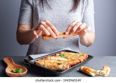 A Caucasian Woman Is Eating Traditional Sigara Boregi, A Turkish Phyllo Dough Pastry Roll Made With Cheese Or Meat Stuffing And Served With Fresh Parsley.