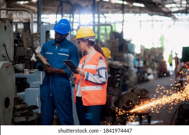 Kaukasische Ingenieurin und afrikanische Technikerin Maschine arbeitet in der Fabrik und überprüft Maschinen, die in der Mitte der Funken von der Reparatur der Maschine zu gefährden.