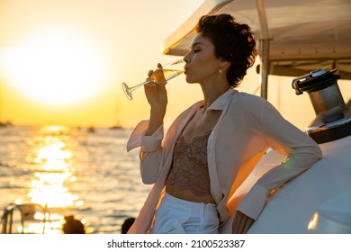 Caucasian woman enjoy outdoor luxury lifestyle with drinking champagne while catamaran boat sailing at summer sunset. Beautiful female relaxing outdoor leisure activity with tropical travel vacation