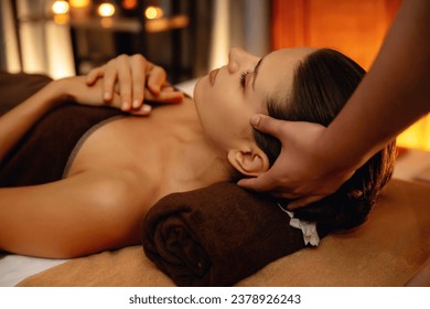 Caucasian woman enjoying relaxing anti-stress head massage and pampering facial beauty skin recreation leisure in warm candle lighting ambient salon spa in luxury resort or hotel. Quiescent - Shutterstock ID 2378926243