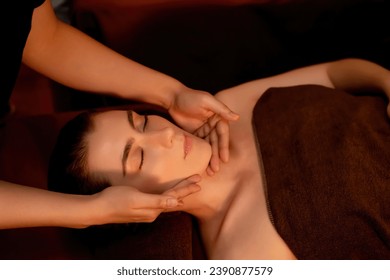 Caucasian woman enjoying relaxing anti-stress head massage and pampering facial beauty skin recreation leisure in warm candle lighting ambient salon spa in luxury resort or hotel. Quiescent - Shutterstock ID 2390877579
