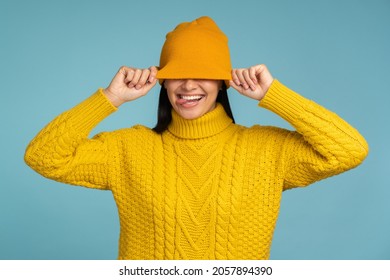 Caucasian Woman Feeling Great During Freezing Weather Wearing Yellow Sweater And Warm Hat And Showing Tongue With Funny Mood 