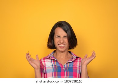 Caucasian woman grimacing screwed up her eyes. Young brunette tasted sour food. Isolated on yellow background. Copy space.