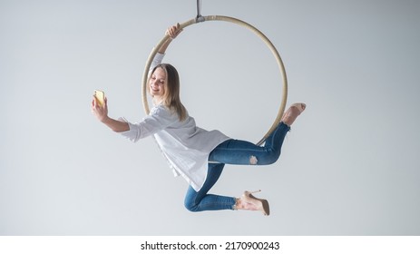 Caucasian Woman Gymnast On An Aerial Hoop Takes A Selfie On A Smartphone. 