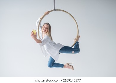 Caucasian Woman Gymnast On An Aerial Hoop Takes A Selfie On A Smartphone. 