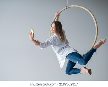 Caucasian Woman Gymnast On An Aerial Hoop Takes A Selfie On A Smartphone. 