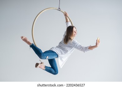 Caucasian Woman Gymnast On An Aerial Hoop Takes A Selfie On A Smartphone. 