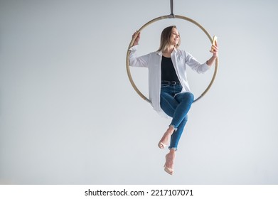 Caucasian Woman Gymnast On An Aerial Hoop Takes A Selfie On A Smartphone. 