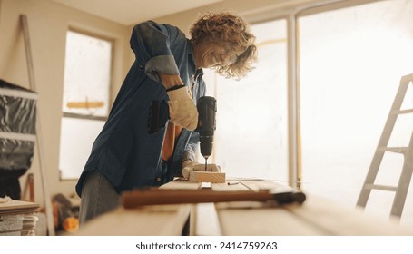 Caucasian woman happily renovates her kitchen, using hand tools and carpentry equipment. She skillfully upgrades her home, installing baseboards and working with wood with gloves and safety goggles on - Powered by Shutterstock