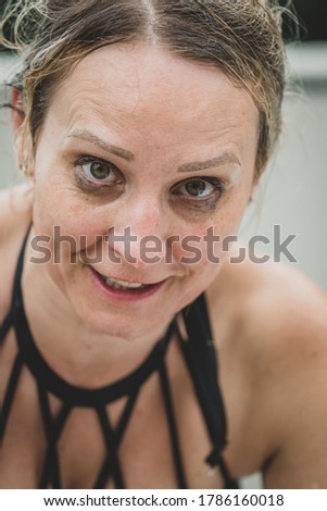 Caucasian woman in her 40s displaying expressions on her face whilst at an outdoor pool, spa and garden.