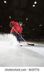 Caucasian Woman Hockey Player Sliding Kicking Up Ice.