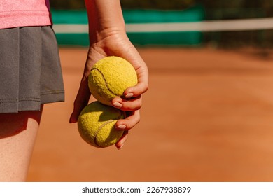 Caucasian woman hold yellow green balls, playing tennis match on clay court surface on weekend free time sunny day. Female player ready to serve, wear skort. Professional sport concept
 - Powered by Shutterstock