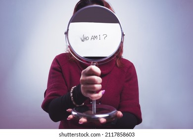 caucasian woman holds a mirror in her hand with the iscription who am i on white background - Shutterstock ID 2117858603