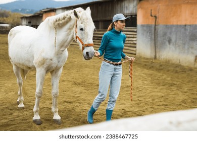 Caucasian woman horse holder leading white horse on farm. - Powered by Shutterstock