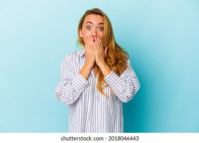 Caucasian woman isolated on blue background shocked, covering mouth with hands, anxious to discover something new.