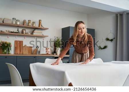 Caucasian woman laying table with a white tablecloth 