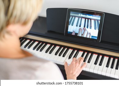 caucasian woman learning to play piano with video lessons. Concept of virtual learning. Selective focus on hand - Powered by Shutterstock