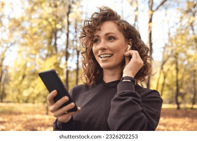 Caucasian woman listening music from mobile phone during the jogging  - Powered by Shutterstock