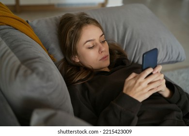 Caucasian Woman Lying Down On The Couch And Using Mobile Phone