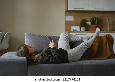 Caucasian Woman Lying Down On The Couch And Using Mobile Phone