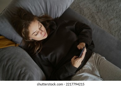 Caucasian Woman Lying Down On The Couch And Using Mobile Phone