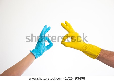 Caucasian woman and man hands and arms in blue and yellow latex gloves doing the OK sign isolate on white 2020