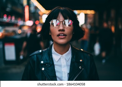 Caucasian Woman In Optical Spectacles With Neon Reflection Of Lights Standing At Urbanity During Travel Vacations For Visiting New York, Attractive Hipster Girl In Trendy Apparel Going Out