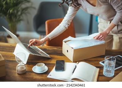  Caucasian woman, the owner of a startup business, is looking at a new order, satisfied with the box at home, preparing to deliver a package in a wardrobe chain. The concept of shopping online