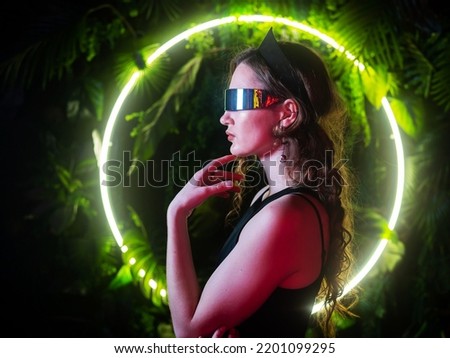Caucasian woman in panoramic sunglasses against the background of an annular neon lamp in plants. 