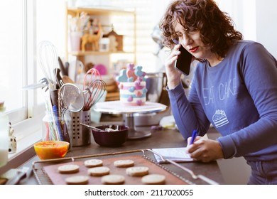 Caucasian woman pastry chef taking note of an order over the phone. Selling to customers. Selective focus. - Shutterstock ID 2117020055