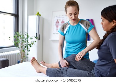 Caucasian woman physiotherapist strectching the leg and knee of a mid-adult chinese female patient sitting on a massage table - Powered by Shutterstock