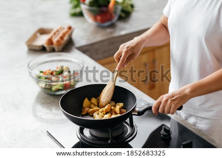 caucasian woman preparing chiken breasts , healthy meal in her rustic eco open kitchen