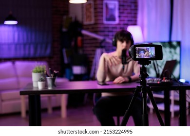 Caucasian woman recording online podcast discussion on camera, vlogging live channel content. Female influencer filming video conversation with audience, using streaming equipment.