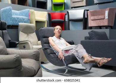 Caucasian Woman Shopping For Furniture, Recliner And Home Decor In Store. Lady Sitting On Rocking Chair Imagining Her New Home Architectural Arrangement.