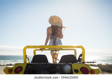 Caucasian woman sitting on beach buggy by the sea wearing straw hat looking toward sea. beach break on summer holiday road trip. - Powered by Shutterstock