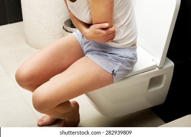 Caucasian woman is sitting on the toilet.
