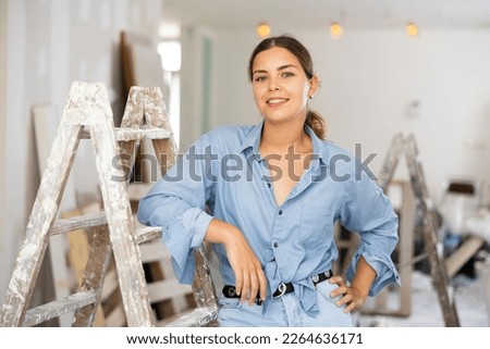 Caucasian woman standing in apartment during repair works, smiling and looking at camera. Stockfoto © 