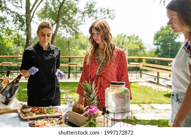 Caucasian Woman Standing By The Female Sommelier In Sunny Summer Day Talking About Food And Wine Helping Them To Make A Decision To Pick The Flavor - Real People Party And Celebration Summer Concept