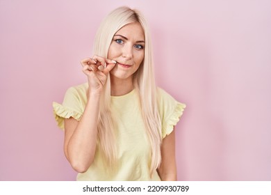 Caucasian Woman Standing Over Pink Background Mouth And Lips Shut As Zip With Fingers. Secret And Silent, Taboo Talking 