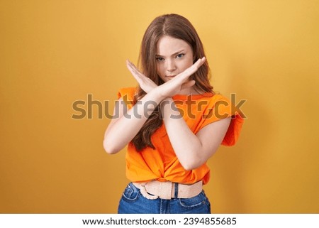 Caucasian woman standing over yellow background rejection expression crossing arms doing negative sign, angry face 