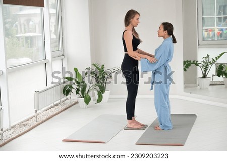 Caucasian woman stands on sadhu boards with therapist support.