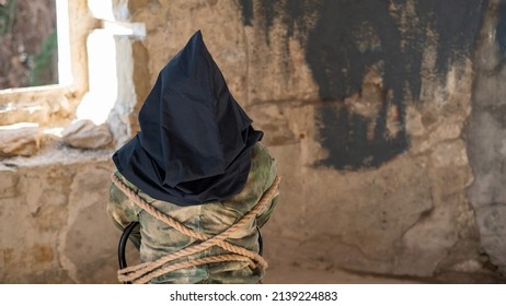 Caucasian woman is taken hostage tied with a rope and with a black bag on her head. 