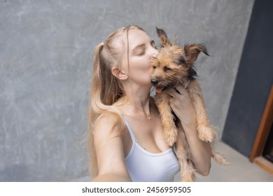 Caucasian woman  taking selfie with her Yorkshire terrier dog while kissing her with love - Powered by Shutterstock